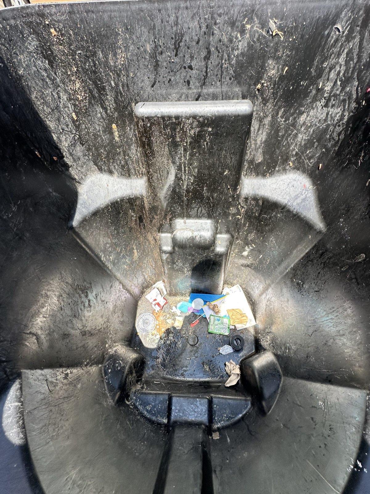 The inside of a trash bin caked with grime and stuck-on trash before cleaning